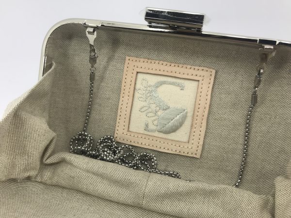 Clutch handmade em couro com o logotipo da marca bordada manualmente a seda natural.
